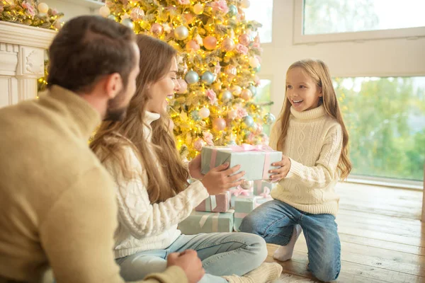 Young family sitting near christmas tree and feeling happy — Stock Photo, Image