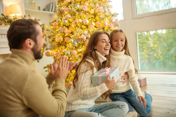 Jonge familie zit in de buurt van de kerstboom en zich gelukkig voelen — Stockfoto