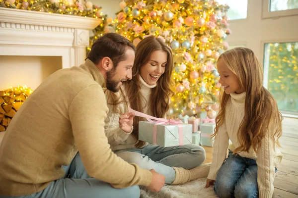 Keluarga muda duduk di lantai dan bertukar hadiah Natal — Stok Foto