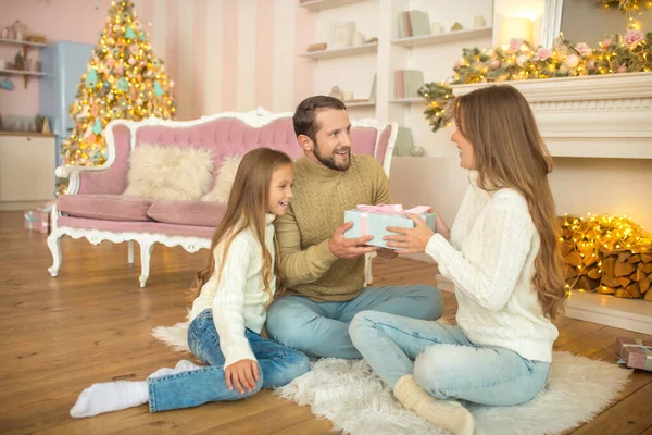 Young family sitting on the floor and exchanging christmas gifts — Stock Photo, Image