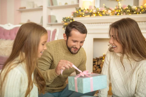 Młoda rodzina siedzi na podłodze i efeeling podekscytowany prezentów świątecznych — Zdjęcie stockowe