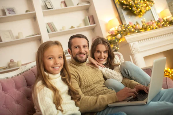 Ouders en hun dochter kijken iets op een laptop — Stockfoto