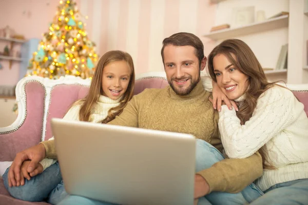 Ouders en hun dochter kijken iets op een laptop — Stockfoto