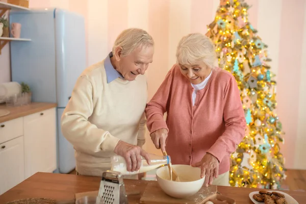 Älteres Paar kocht etwas in der Küche und fühlt sich wohl — Stockfoto