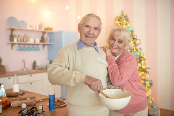 Älteres Paar steht in der Küche, Mann rührt etwas in Schüssel und lächelt — Stockfoto