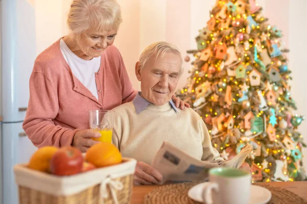 Älteres Paar sitzt in einer dekorierten Küche und sieht zufrieden aus — Stockfoto