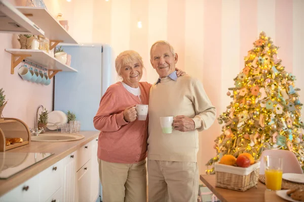 Pareja mayor de pie en la cocina y mirando feliz — Foto de Stock