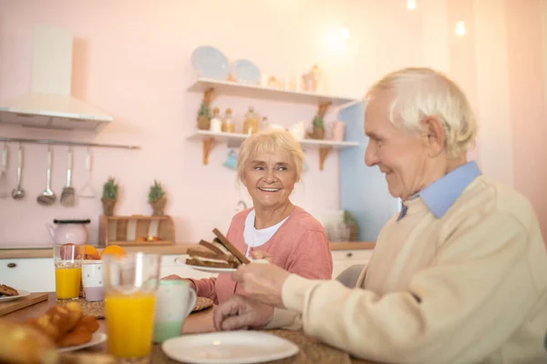 Elderly couple having breafast and looking happy — Stock Photo, Image