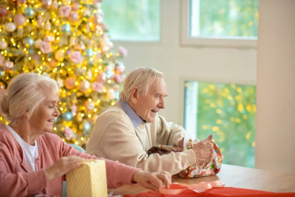 Älteres Paar packt Weihnachtsgeschenke ein und sieht beschäftigt aus — Stockfoto