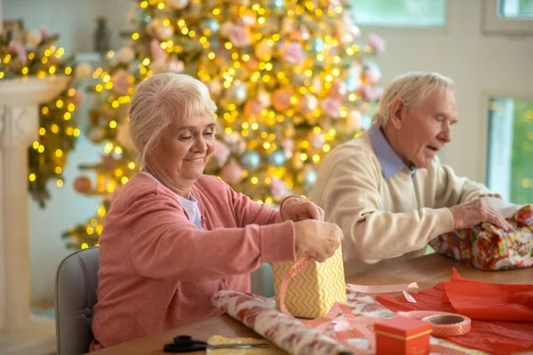 크리스마스 선물을 포장하고 즐거운 기분을 느끼는 연로 한 부부 — 스톡 사진