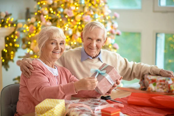 Starsza para przygotowuje prezenty świąteczne i wygląda na szczęśliwą — Zdjęcie stockowe