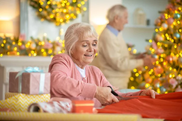 Старшая пара готовит рождественские подарки и украшает елку — стоковое фото