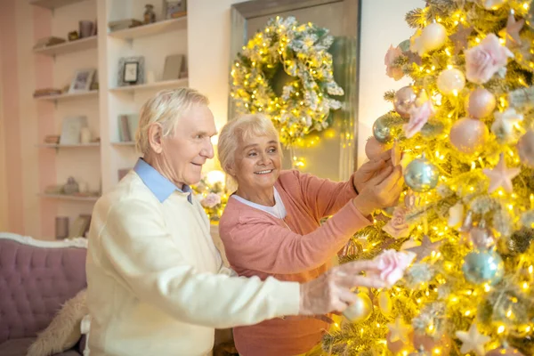 Couple âgé décorer arbre de Noël ensemble et regarder impliqué — Photo