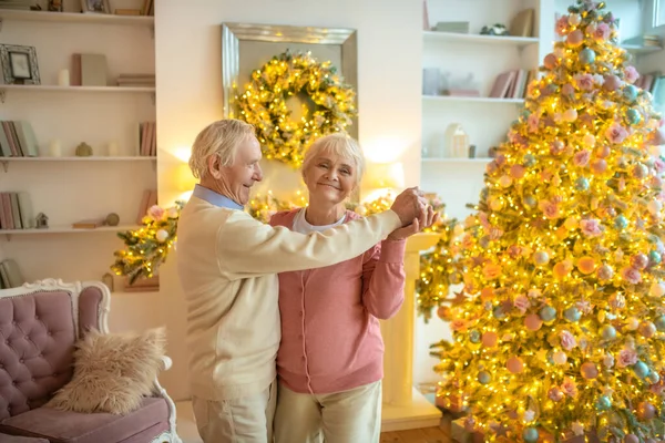 Idős pár táncol közel karácsonyfa és boldognak tűnnek — Stock Fotó