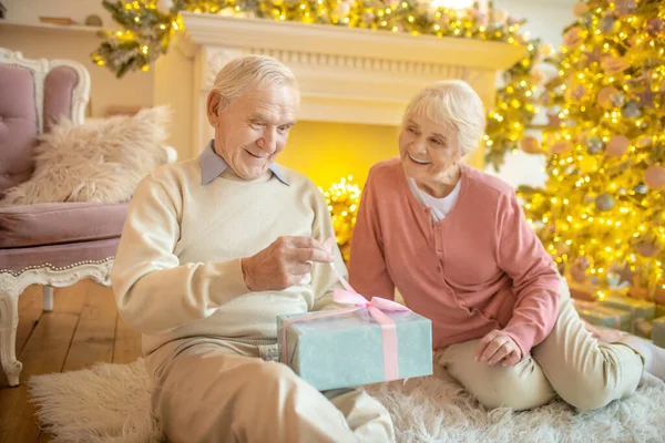 Älterer Mann öffnet Weihnachtsgeschenk seiner Frau — Stockfoto