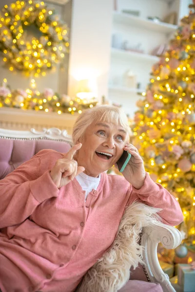 Femme âgée assise sur un canapé et ayant une belle conversation au téléphone — Photo