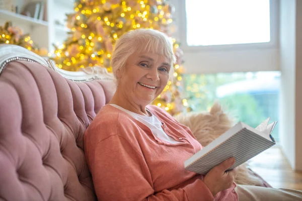 Starší žena čte knihu a hezky se usmívá — Stock fotografie