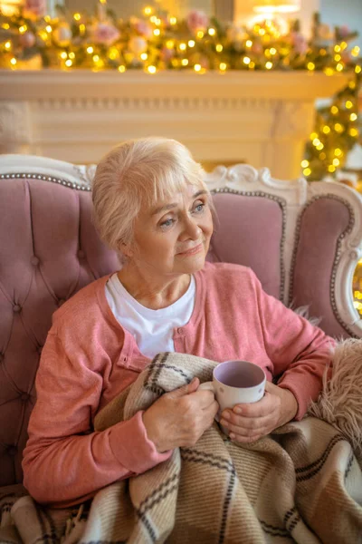 Femme âgée assise sur un canapé avec une tasse de thé — Photo