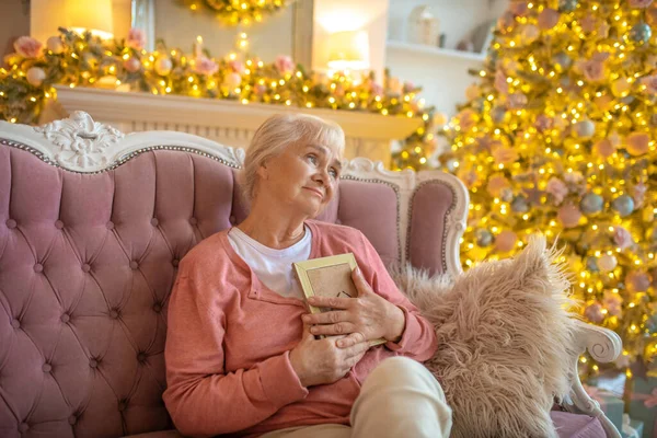 Wanita tua duduk di sofa dengan foto di tangannya dan merasa kesepian — Stok Foto