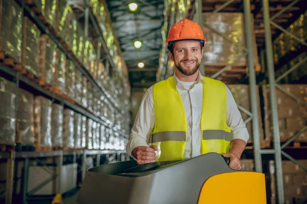 Lagerarbeiter mit orangefarbenem Helm arbeitet und sieht positiv aus — Stockfoto