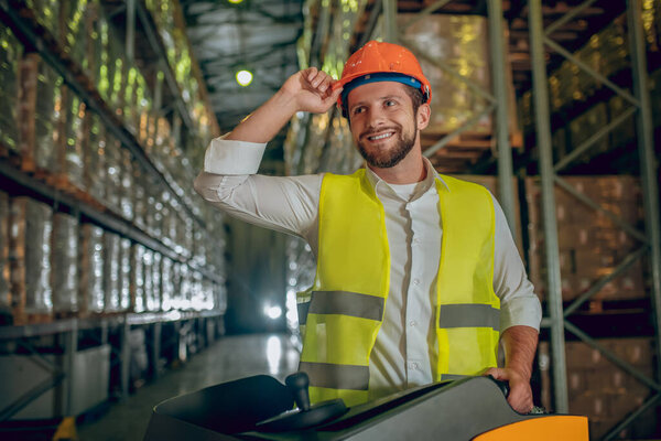 Warehouse worker in orange helmet working and feeling good