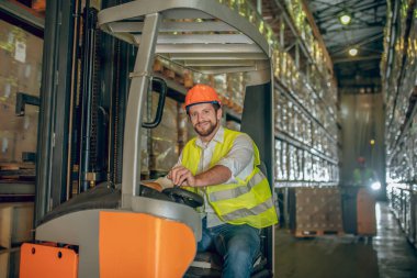 Genç sakallı işçi gülümsüyor ve pozitif görünüyor.