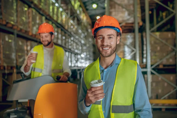 Trabalhadores do armazém em capacetes laranja tendo coffee break — Fotografia de Stock