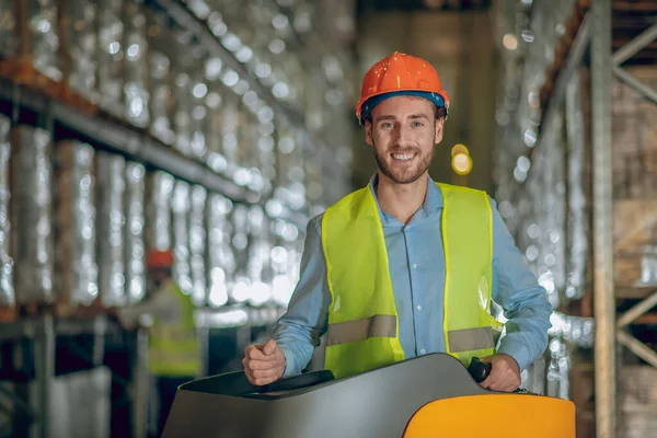 Trabalhador do armazém em capacete protetor sorrindo positivamente — Fotografia de Stock