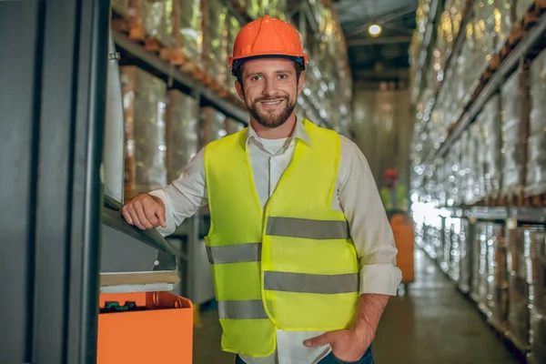 Jonge mannelijke werknemer in geel vest glimlacht positief — Stockfoto