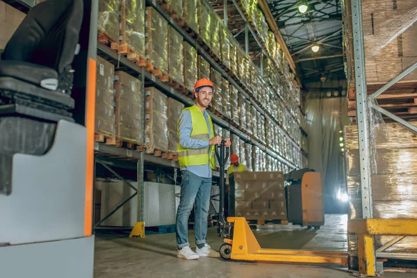 Lavoratore in gilet e casco in piedi nel magazzino — Foto Stock