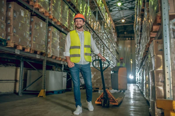 Trabajador con chaleco y casco que lleva el cargador — Foto de Stock