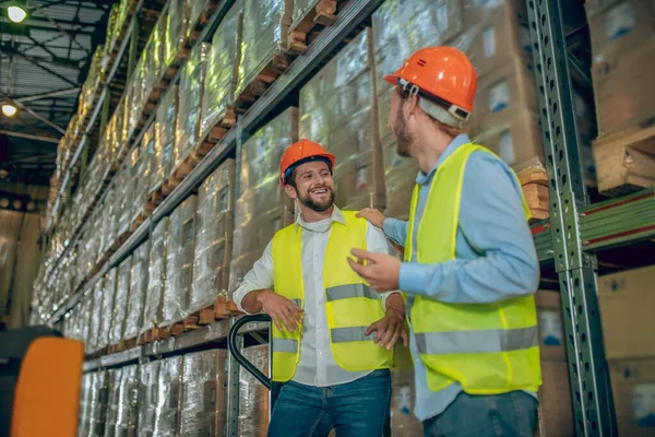 Twee arbeiders in gele vesten praten en kijken tevreden — Stockfoto