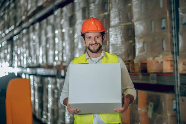 Jonge mannelijke bebaarde werknemer met een doos en glimlach — Stockfoto