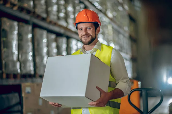 Jonge bebaarde arbeider met een doos en een glimlach — Stockfoto