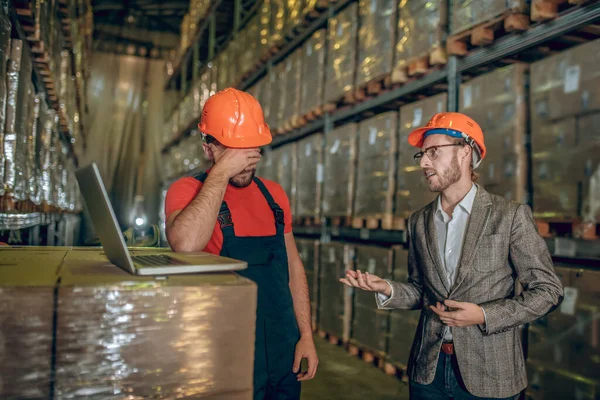 Manager praat met de magazijnmedewerker en bekritiseert zijn werk — Stockfoto