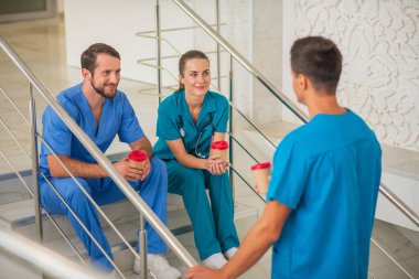 Medical workers sitting on the stairs and having coffee clipart