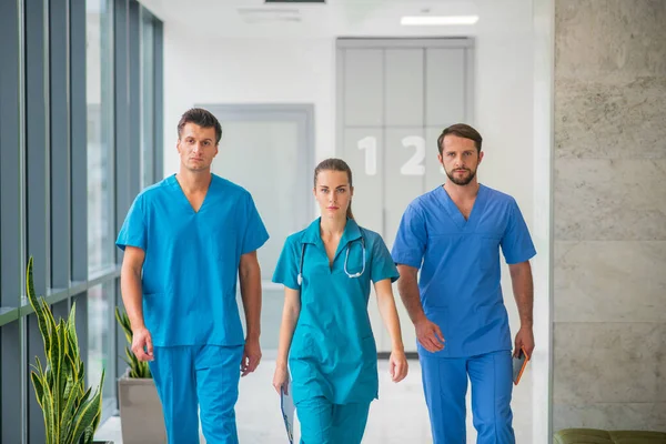 Három orvos együtt sétál a kórház folyosóján. — Stock Fotó