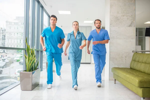 Trois médecins qui courent dans le couloir de l'hôpital sont pressés — Photo