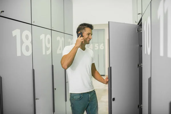 Young male doctor in a changing room talking on the phone and looking involved — Stock Photo, Image
