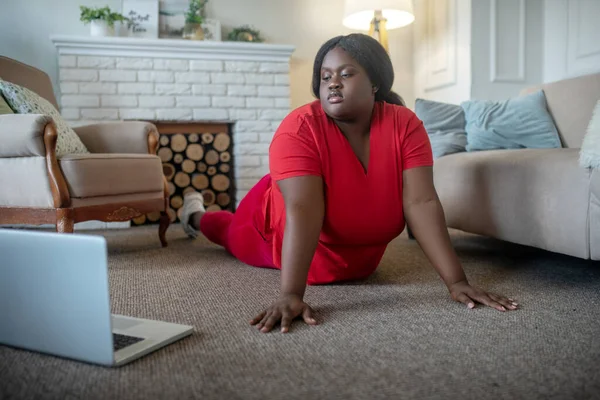 Más tamaño afroamericana mujer teniendo un entrenamiento en línea y de pie en tablón — Foto de Stock