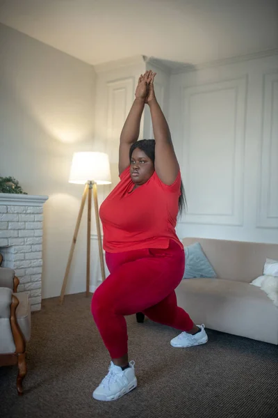 Plus storlek afrikansk amerikansk kvinna gör lungor med armarna upp — Stockfoto