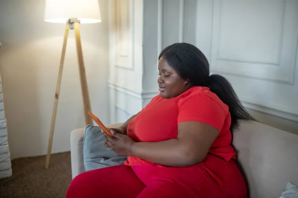 Plus la taille femme afro-américaine passer du temps sur Internet et regarder impliqué — Photo