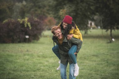 Kırmızı şapkalı kız erkek arkadaşının arkasında oturuyor ve kendini harika hissediyor.