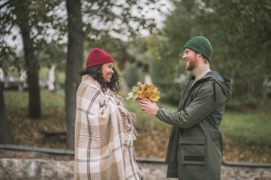 Adam sevgilisine bir demet sarı yaprak getiriyor.