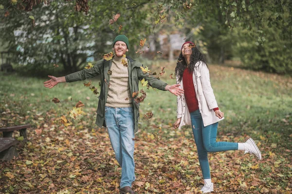 Young couple enjoying playing with beautiful autumn leaves — Stock Photo, Image