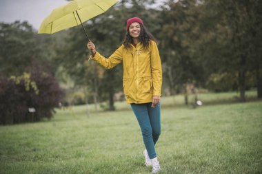 Sarı şemsiyeli şirin mulatta neşeli görünüyor.