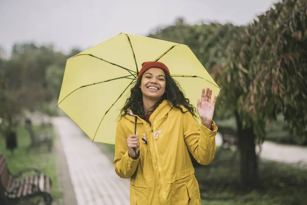 Cute mulatta with yellow umbrella looking happy — Stock Photo, Image