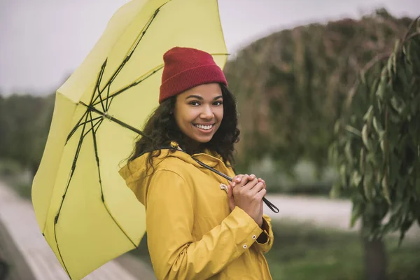 Cute mulatta with yellow umbrella smiling happily — Stock Photo, Image