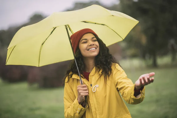Söt mulatta med gult paraply ser glad ut — Stockfoto