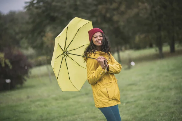 Söt mulatta med gult paraply ser glad ut — Stockfoto